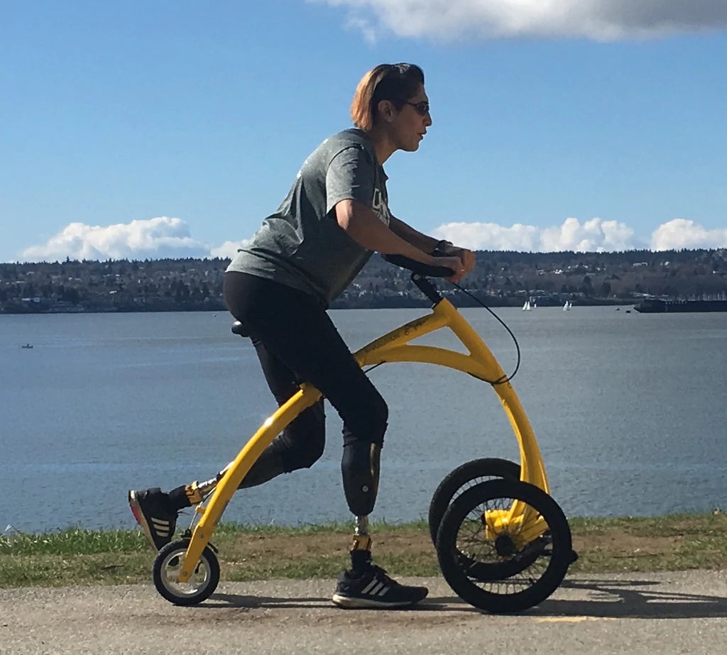 A woman riding an Alinker along a seawall