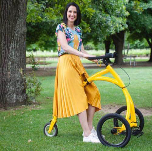 An Alinker rider in a park, the three-wheeled frame holding itself upright